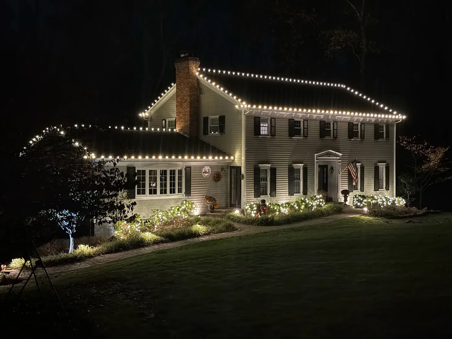 Angled view of a home and entry outlined with warm white Christmas lights.