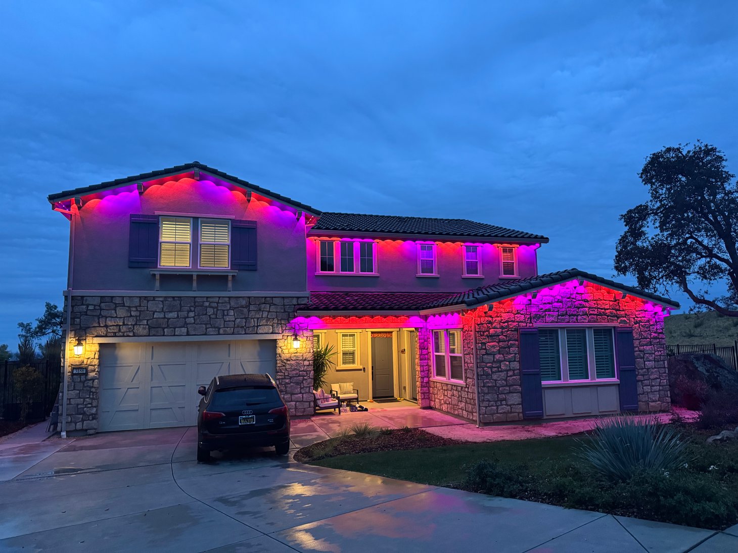 Home with pink and purple permanent roofline lighting at dusk.