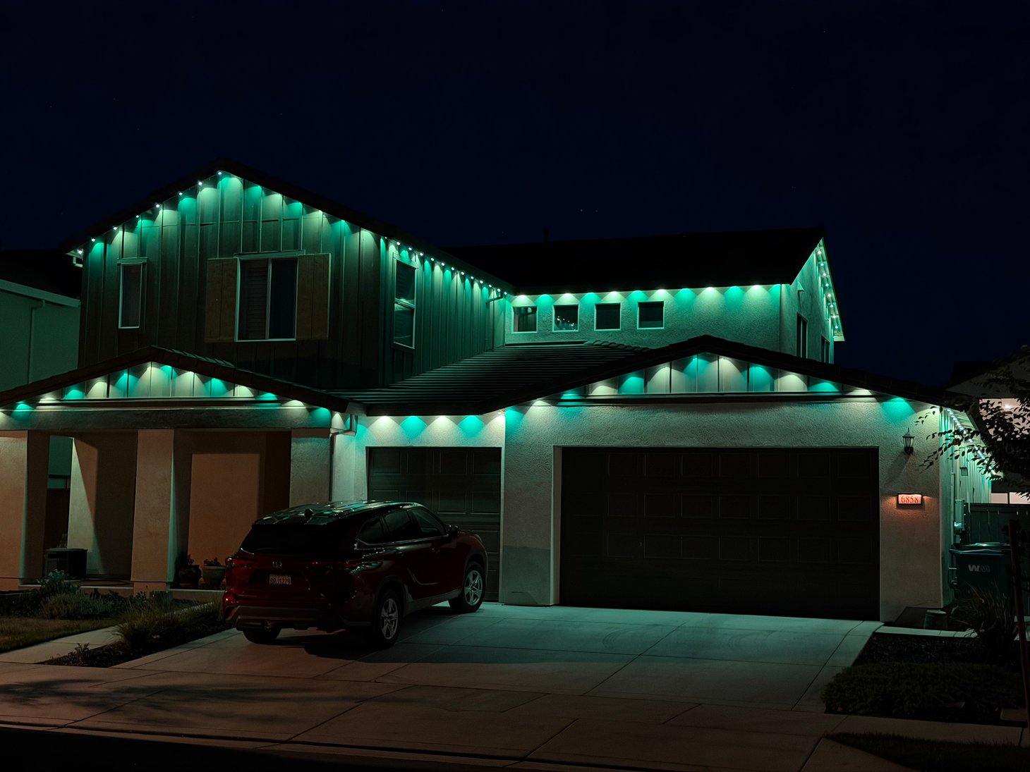 Home with green permanent roofline lighting after dark.