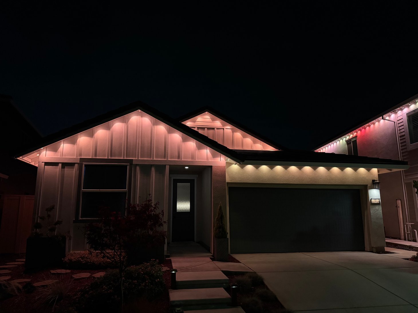 Single-story home with soft warm and pink permanent lighting along the roofline.